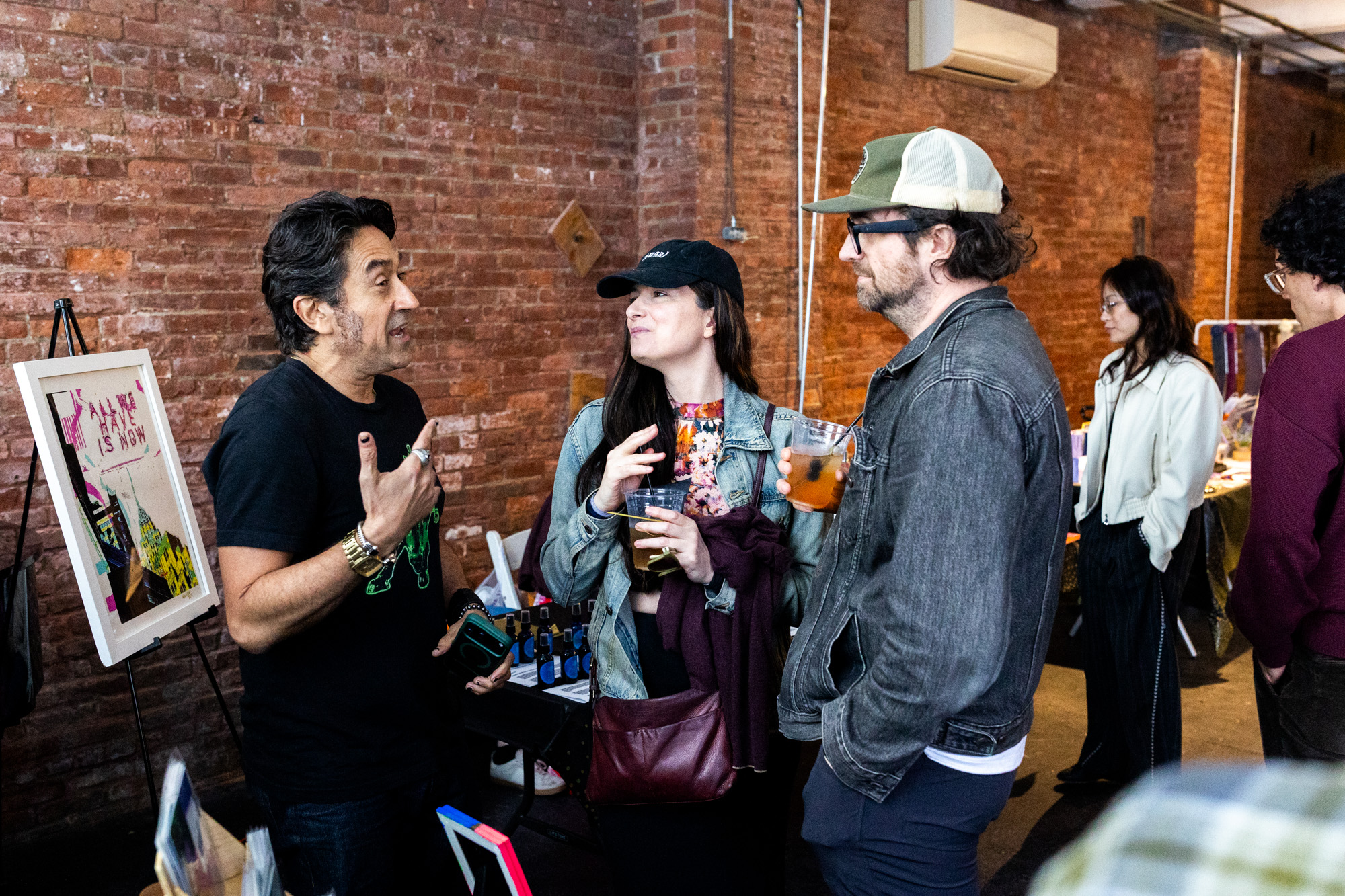 Three attendees in conversation against the warm brick wall