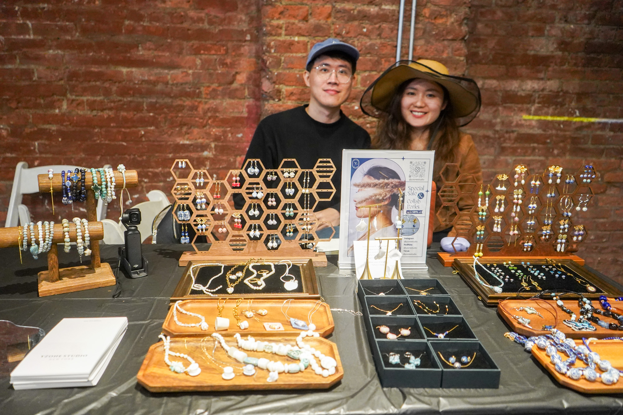 Jewelry vendor couple smiling behind their hexagonal display at the venue